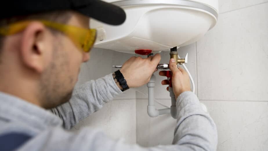 Plumber repairing a water heater, focusing on plumbing maintenance in a residential setting, highlighting essential plumbing services.