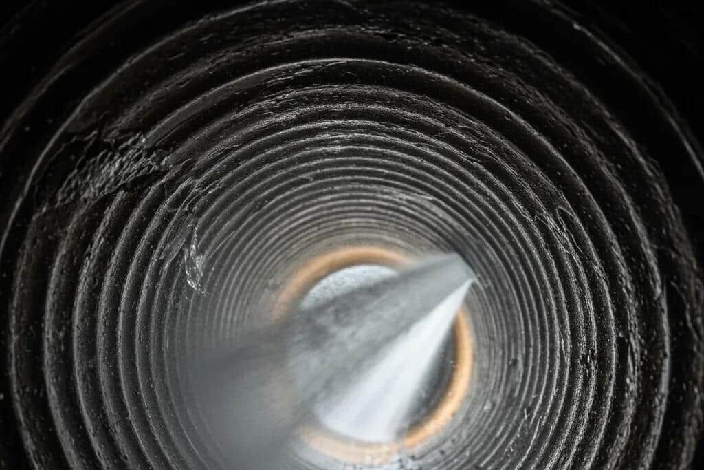 Hydro jetting process cleaning interior of sewer pipe with high-pressure water for drain blockage removal.